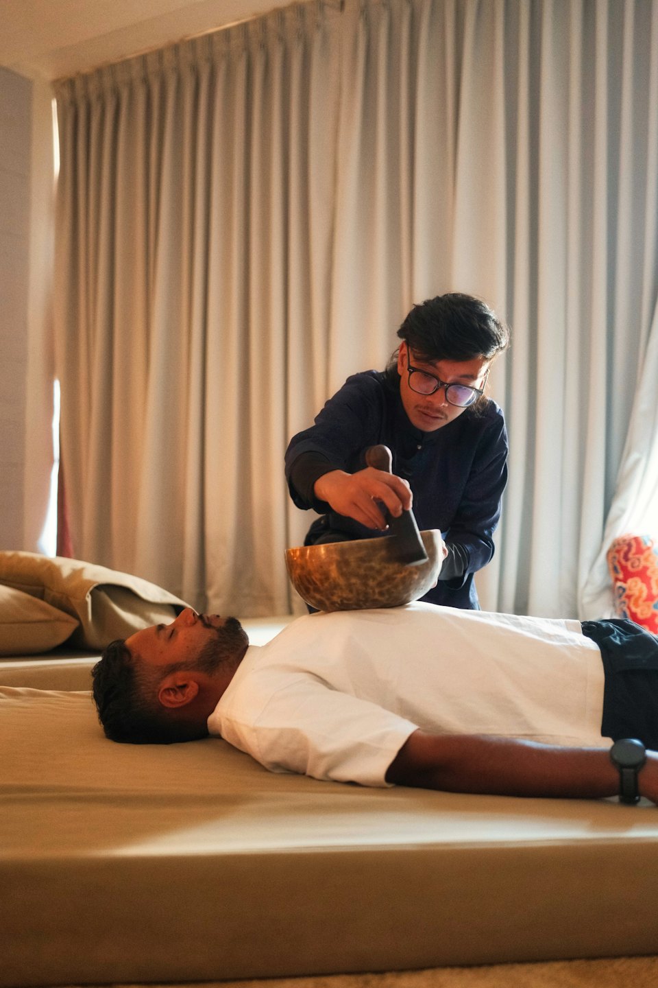 Operatore olistico posiziona una campana tibetana sulla schiena di un cliente.